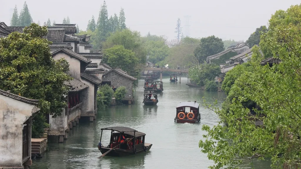 古い中国の水郷町で木造の家と運河、そして遊覧用のボートが見える風景。